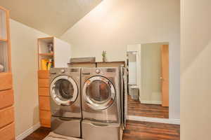 Laundry room featuring vaulted ceiling, separate washer and dryer, and dark wood-type flooring