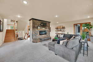 Carpeted living room with a stone fireplace and recessed lighting