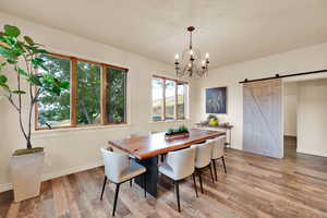 Dining area with a barn door, a chandelier, and light wood-type flooring