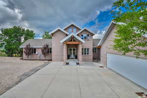 View of front of home with french doors, brick siding, concrete driveway, and roof with shingles