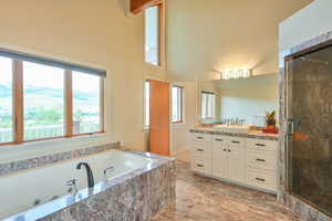 Full bath featuring a tub with jets, a stall shower, vanity, a high ceiling, and a mountain view