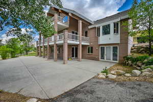 Back of property with a balcony, brick siding, and a patio