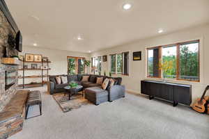 Living room featuring a stone fireplace, carpet, and recessed lighting
