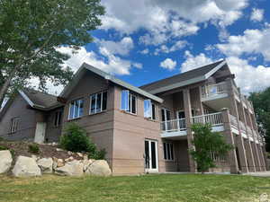 View of side of property with brick siding, a yard, and a balcony