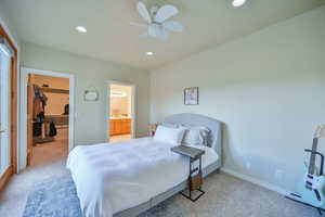 Bedroom with a spacious closet, light carpet, ceiling fan, recessed lighting, and ensuite bath