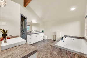 Bathroom featuring a jetted tub, two vanities, beam ceiling, a shower stall, and high vaulted ceiling