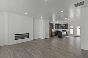 Unfurnished living room with a large fireplace, dark wood finished floors, recessed lighting, and a textured ceiling
