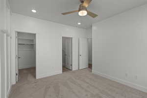 Unfurnished bedroom featuring a spacious closet, light colored carpet, ceiling fan, and recessed lighting