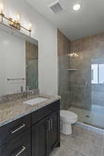 Bathroom featuring vanity, light tile patterned floors, a stall shower, and a chandelier