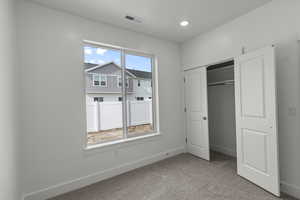 Unfurnished bedroom featuring light colored carpet and a closet
