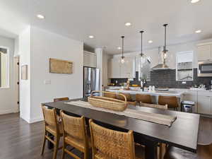 Kitchen with a kitchen island with sink, decorative light fixtures, dark wood finished floors, recessed lighting, and stainless steel appliances