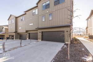 Rear view of property with board and batten siding, driveway, and a garage