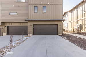 View of front of property featuring board and batten siding, an attached garage, and driveway