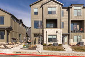View of front of home featuring stone siding, board and batten siding, and a balcony