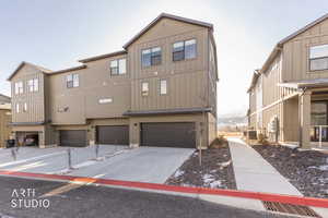 Back of property featuring board and batten siding, concrete driveway, and a garage