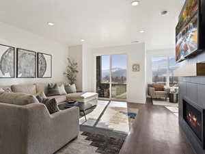Living room with recessed lighting, a tiled fireplace, and dark wood finished floors