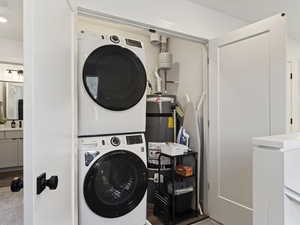 Washroom with stacked washer and clothes dryer and secured water heater