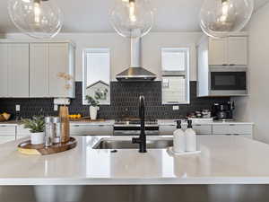 Kitchen with white cabinets, light stone counters, and wall chimney exhaust hood