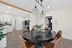 Dining area with recessed lighting, a barn door, light wood finished floors, and a textured ceiling