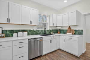 Kitchen featuring dishwasher, white cabinets, light wood finished floors, and light stone countertops