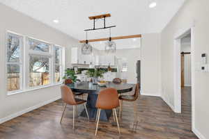 Dining area with recessed lighting, dark wood-type flooring, a textured ceiling, and a barn door