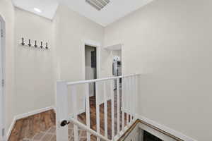 Corridor with an upstairs landing and wood finished floors