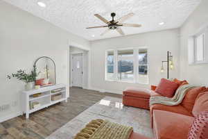 Living area with wood finished floors, recessed lighting, a ceiling fan, and a textured ceiling