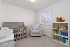Bedroom featuring a crib and light carpet