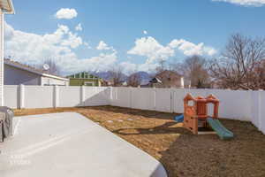 Fenced backyard with a mountain view, a playground, and a patio