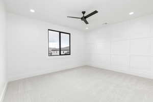 Unfurnished room featuring light colored carpet, ceiling fan, recessed lighting, and a decorative wall