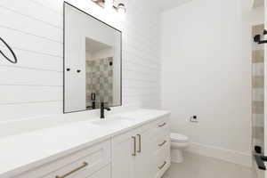 Full bathroom featuring vanity, a stall shower, and wooden walls