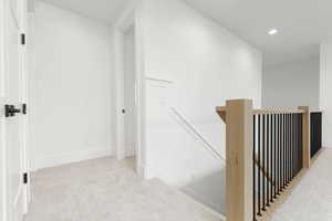 Corridor featuring an upstairs landing, light colored carpet, and recessed lighting