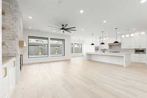 Kitchen with glass insert cabinets, white cabinets, a large island with sink, open floor plan, and open shelves