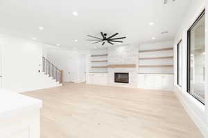 Unfurnished living room featuring a ceiling fan, light wood-style floors, a fireplace, and recessed lighting