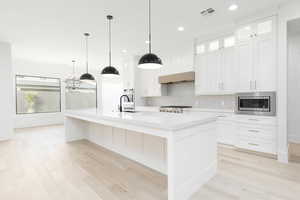 Kitchen with a large island, light wood-style flooring, and white cabinetry