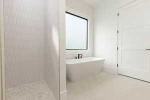 Full bathroom featuring a freestanding tub, light tile patterned floors, and tiled shower
