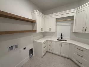 Washroom with hookup for an electric dryer, cabinet space, and hookup for a washing machine