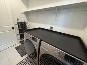Laundry room with light tile patterned floors and washer and clothes dryer