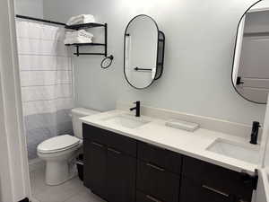 Bathroom featuring a shower with shower curtain, double vanity, and light tile patterned flooring