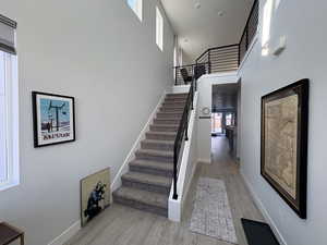 Staircase with a towering ceiling and wood finished floors