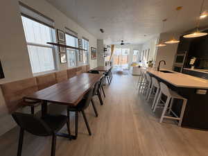 Dining room with light wood finished floors, a textured ceiling, and ceiling fan