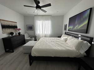 Bedroom featuring a textured ceiling, a ceiling fan, and wood finished floors