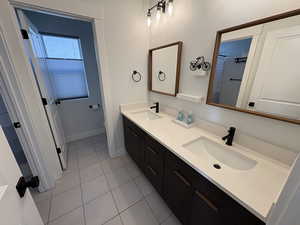 Bathroom featuring double vanity, light tile patterned floors, and a shower with shower curtain
