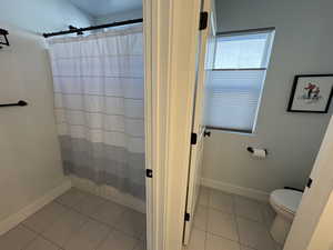 Bathroom with a shower with curtain and light tile patterned floors