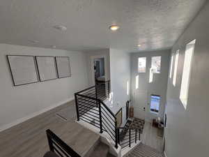 Entrance foyer featuring wood finished floors, a textured ceiling, plenty of natural light, stairs, and recessed lighting