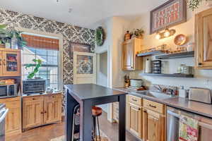 Kitchen with appliances with stainless steel finishes, open shelves, light tile patterned floors, and light brown cabinetry