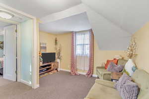 Living area featuring carpet and vaulted ceiling