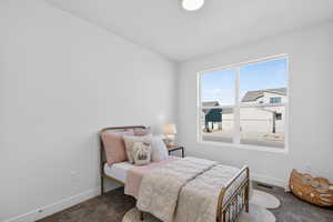 Bedroom with dark colored carpet and baseboards