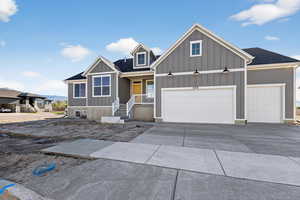 View of front facade featuring board and batten siding, an attached garage, concrete driveway, and covered porch
