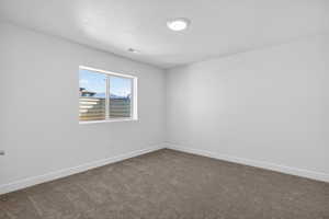Spare room with baseboards and dark carpet